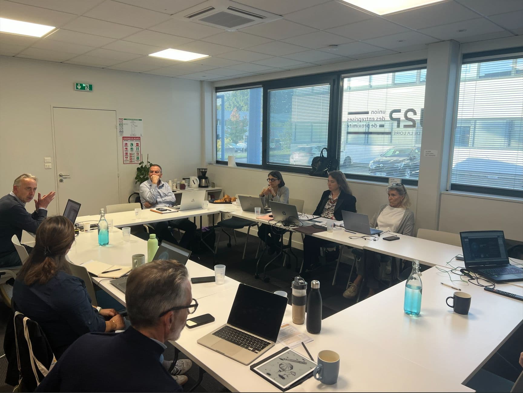 Session de formation IA en petit groupe autour d'une table, participants sur leurs ordinateurs